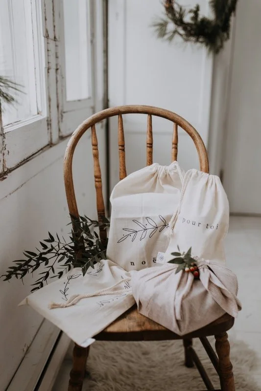 Wrapped gifts on a timber chair beside a softly draped window.