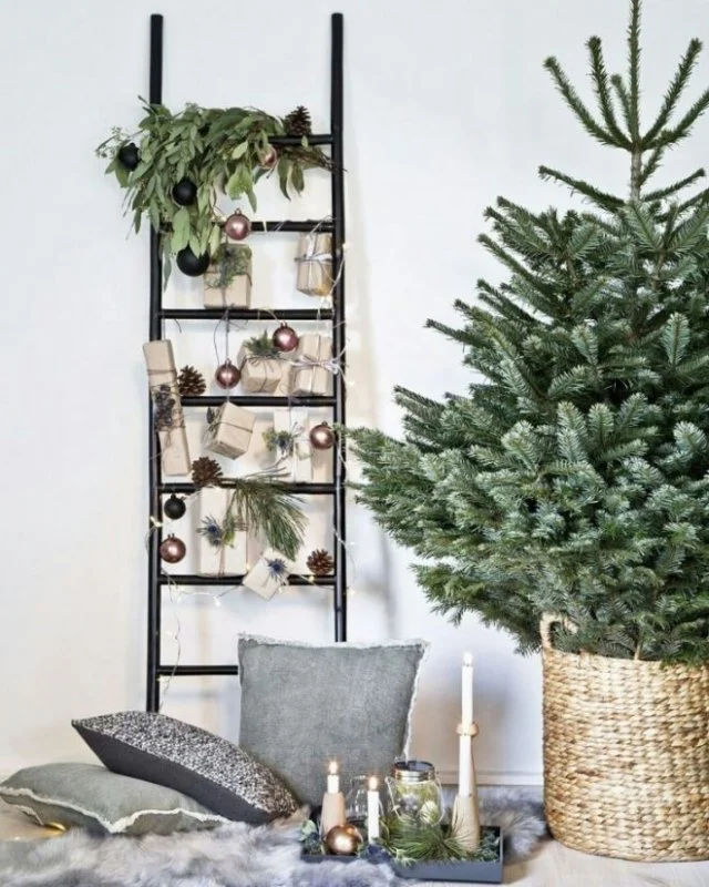 Christmas tree in a woven basket beside a ladder display of small objects.