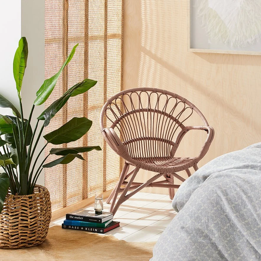 Woven chair and indoor plants beside a pale timber screen.