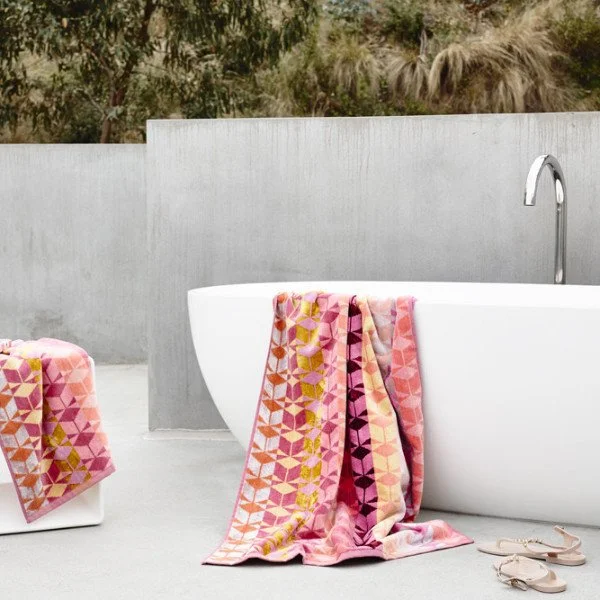 White freestanding outdoor bath with colourful patterned towels.