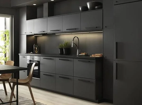 Dark kitchen cabinetry with a curved tap and understated stone surfaces.