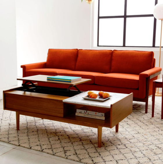 Timber coffee table with open storage beneath a rust-toned sofa.