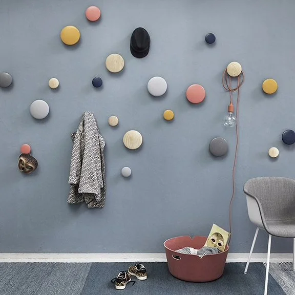 Colourful round wall hooks holding small accessories against a blue-grey wall.