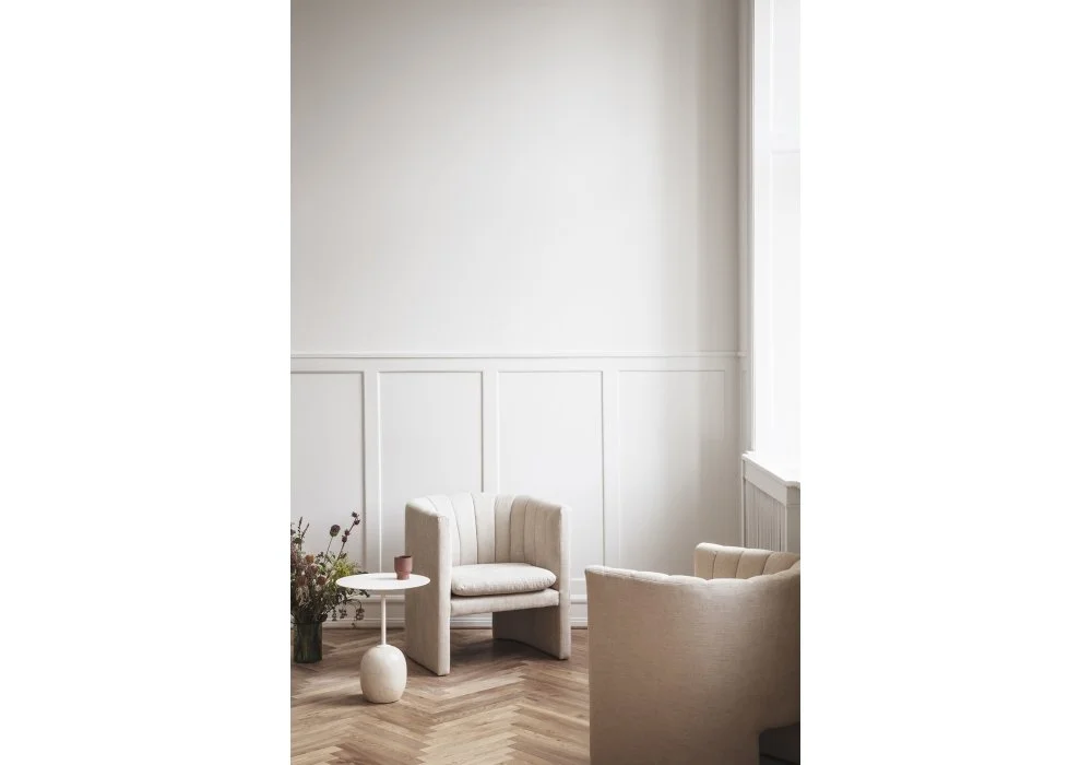 Softly lit pale living room with rounded seating and full-height curtains.