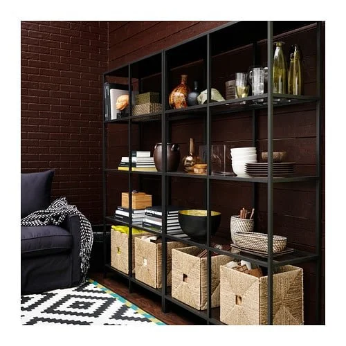 Dark open shelving displaying books, objects and woven storage baskets.