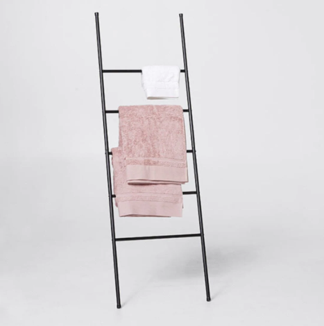 Black ladder-style towel stand displaying pink and white towels.