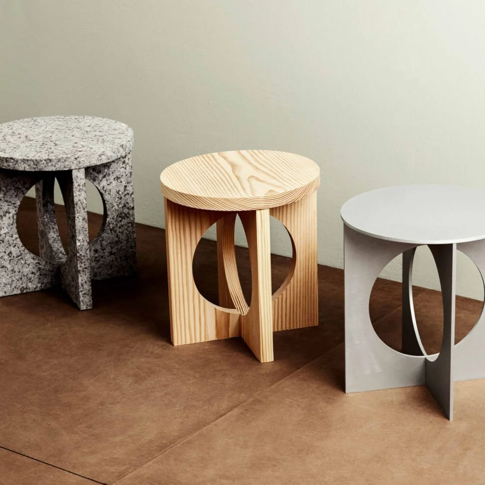 Round sculptural stools in varied materials with circular side openings.