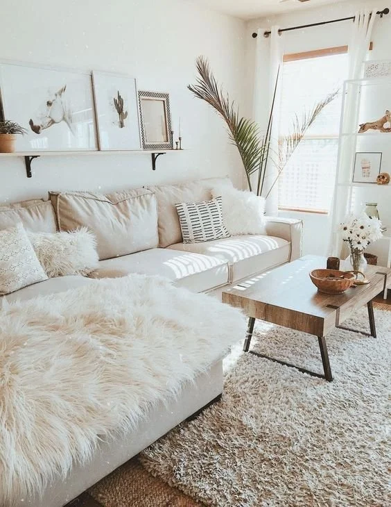 Pale sofa with layered cushions and a soft throw beside a small side table.