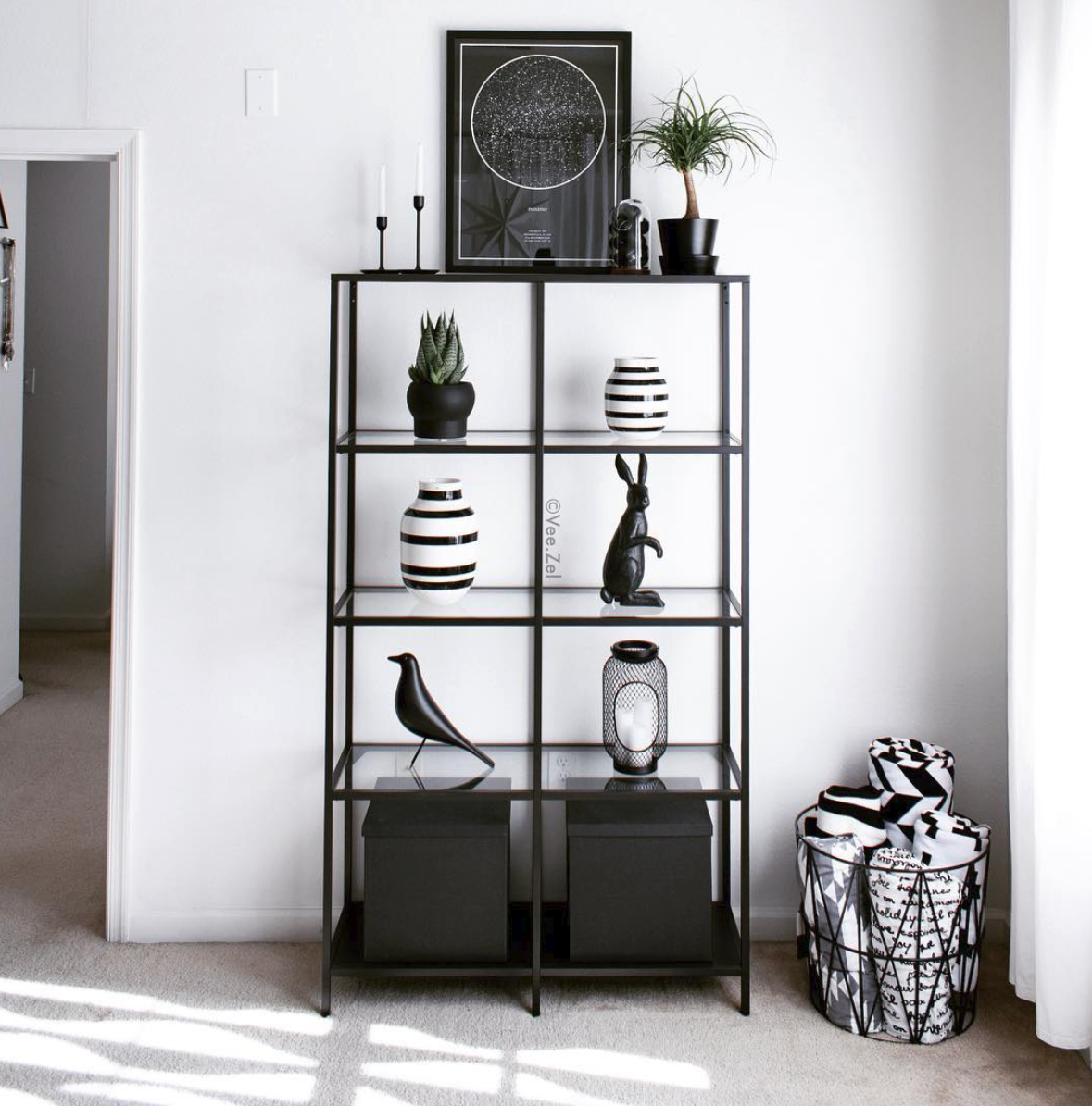 Tall black open shelving displaying sculptural objects and a small plant.