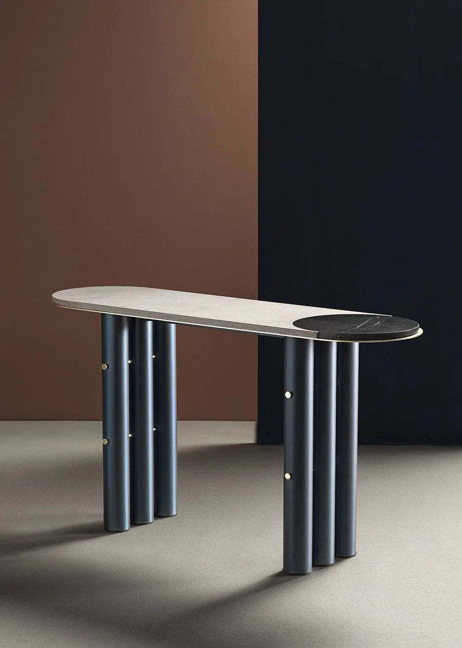 Console table with a pale stone top and grouped dark tubular legs.