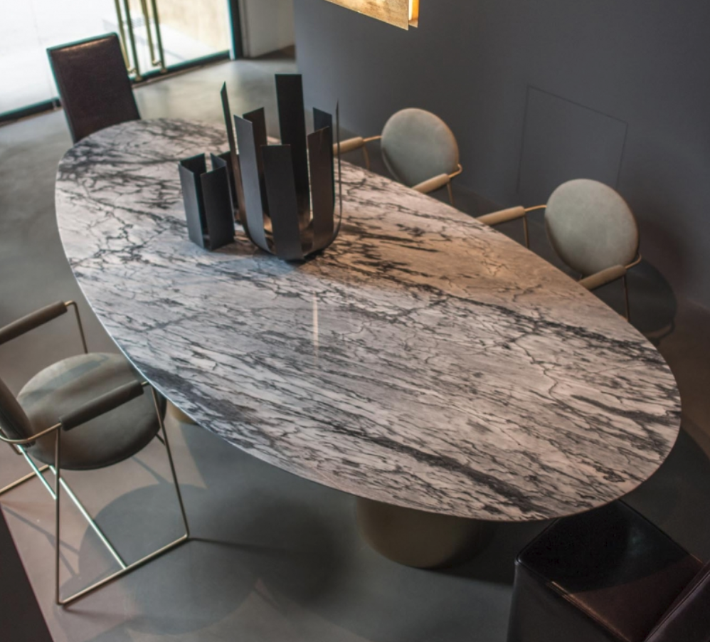 Oval veined stone dining table surrounded by pale chairs.