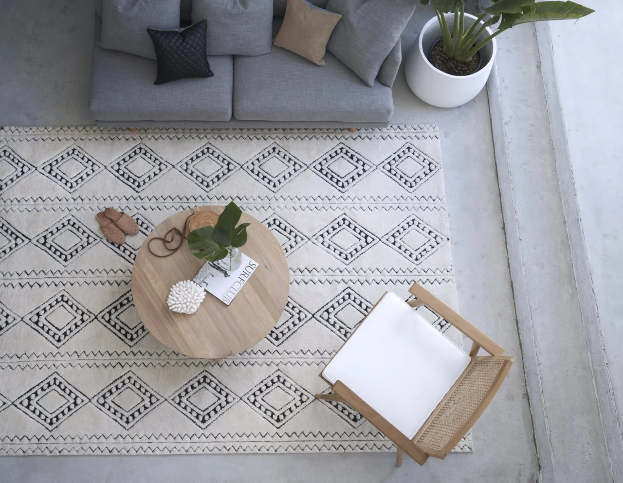 Overhead view of a geometric rug beneath a round table and lounge chairs.