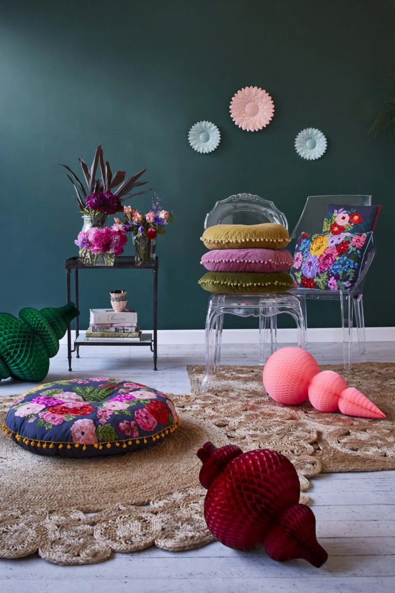 Colourful cushions and decorative objects arranged against a deep green wall.
