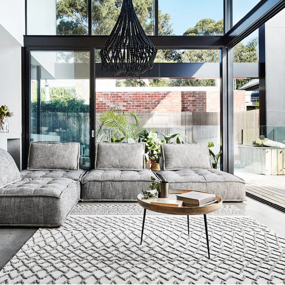 Patterned pale rug beneath seating in a bright glazed living room.