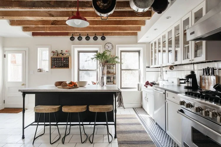 Long patterned runner alongside a dark kitchen island beneath timber beams.