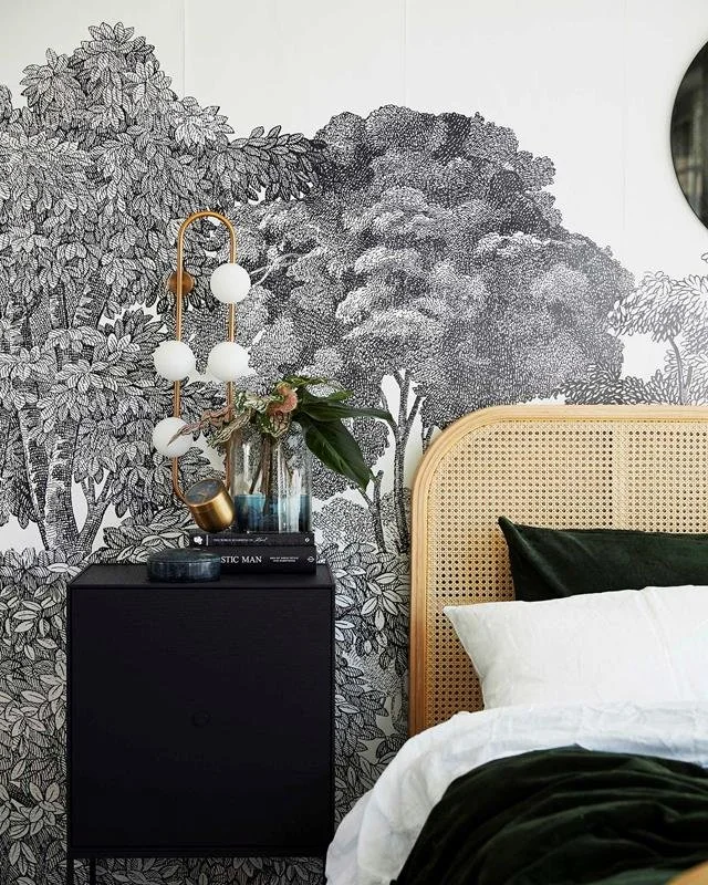 Bedroom with patterned landscape wallpaper and decorative globe lighting.