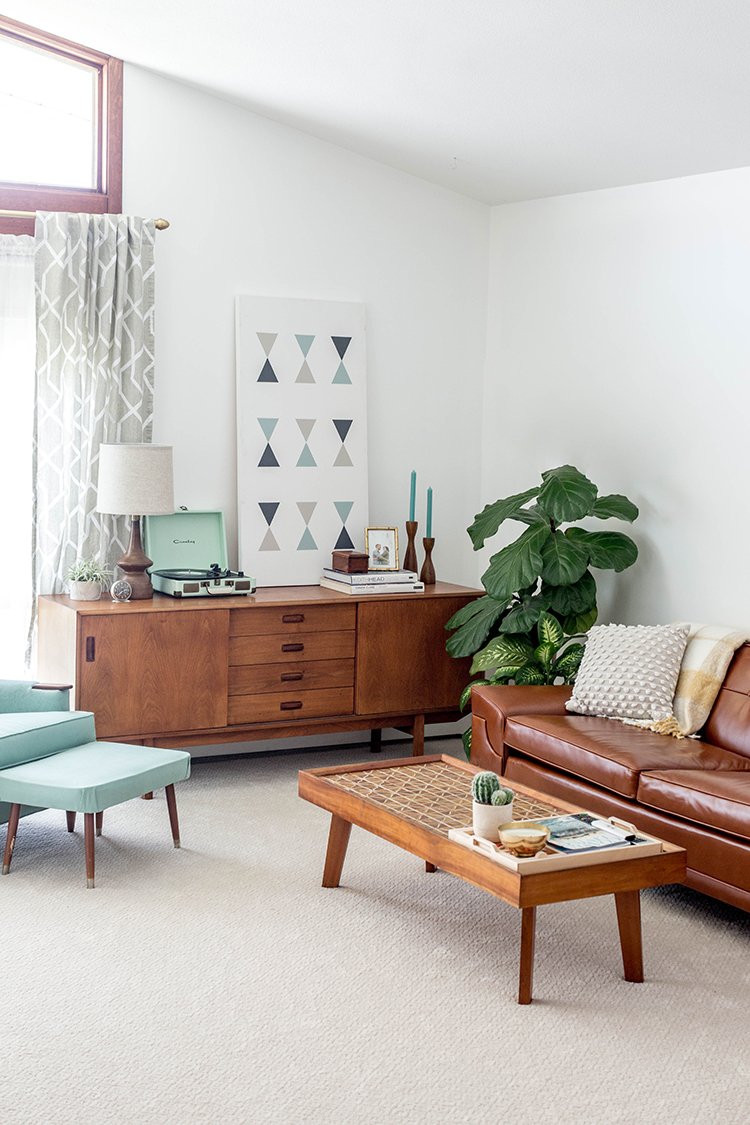Mid-century timber furniture and indoor plants within a pale living room.