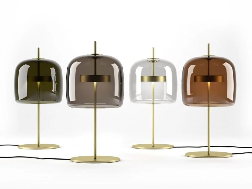 Four rounded glass table lamps with slender brass-toned stems.