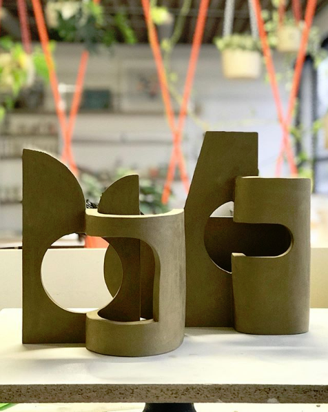 Sculptural green chairs with rounded cut-outs beside bright glazing.