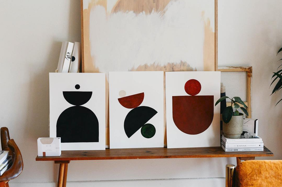 Framed geometric prints arranged on a timber sideboard.