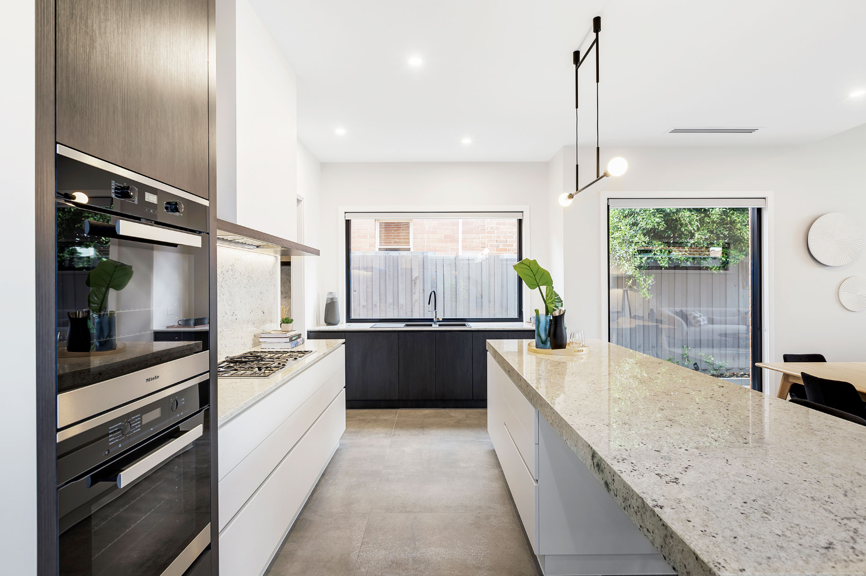 Kitchen with a long veined stone island and integrated appliances.