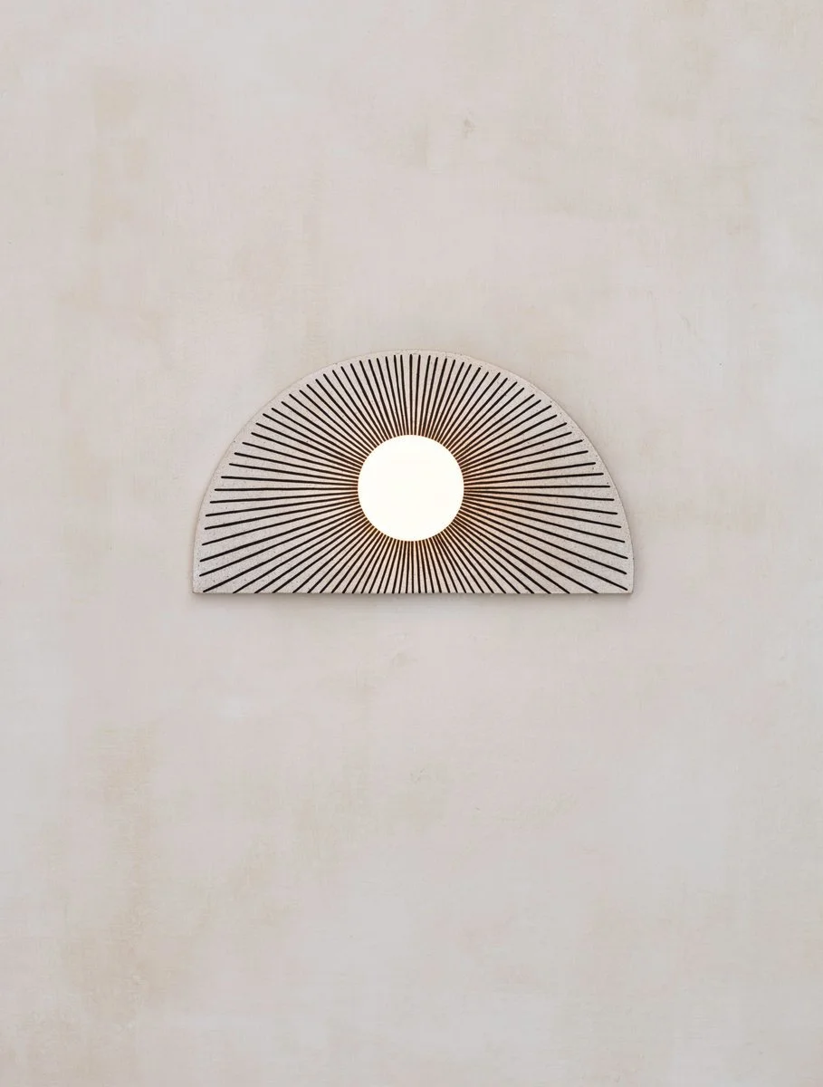 Fan-shaped wall light with a central round globe against a pale wall.