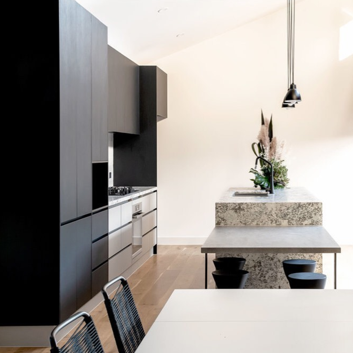 Kitchen with dark tall cabinetry, a pale island and a suspended linear light.