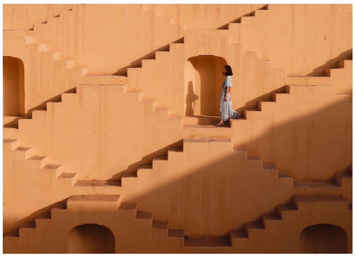 Warm ochre architecture with repeating external staircases and deep shadow lines.