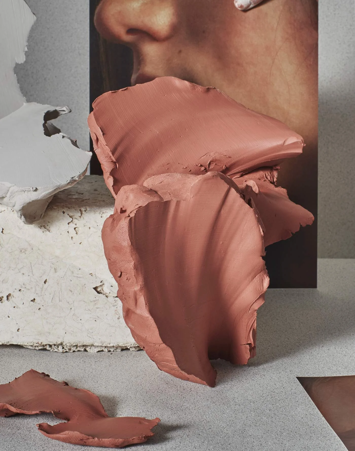 Rust-coloured draped fabric arranged over a pale textured surface.