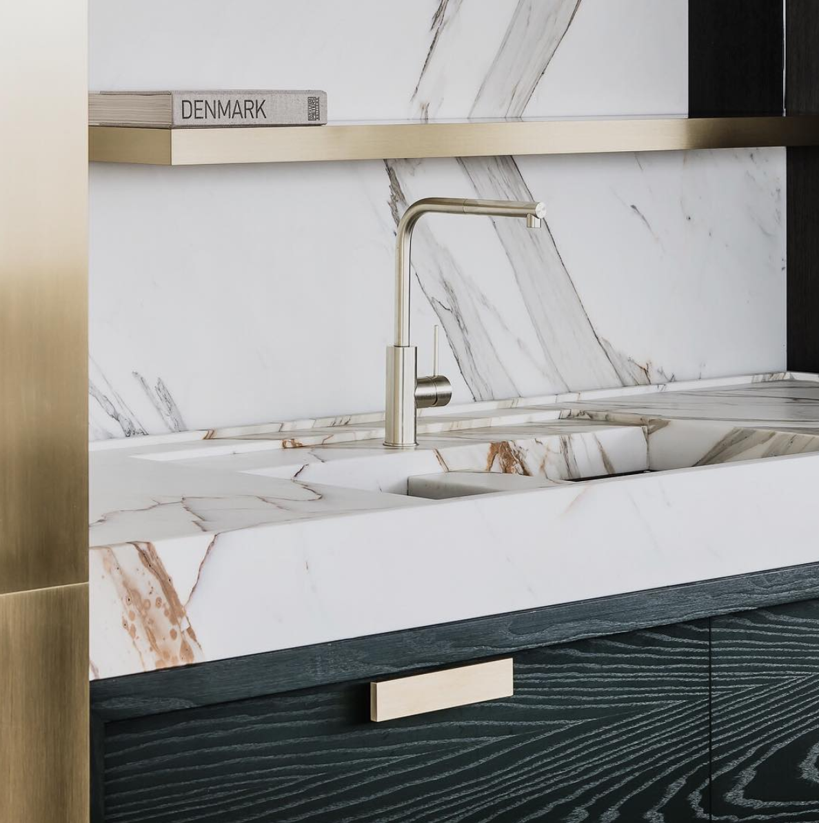 Veined pale stone vanity with dark textured cabinetry and brass-toned details.