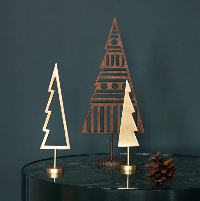 Geometric tree-shaped decorations and candles against a dark green background.