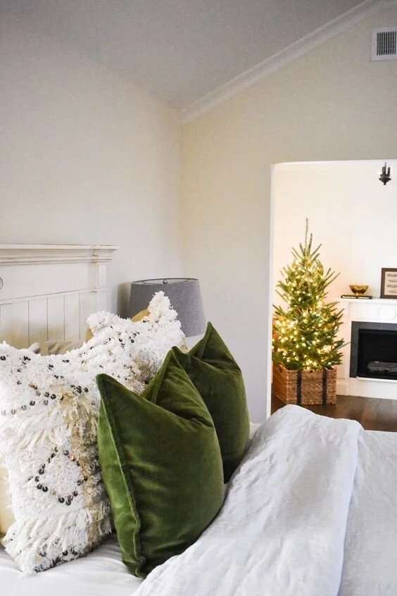 Green velvet cushions against patterned pale bedding.