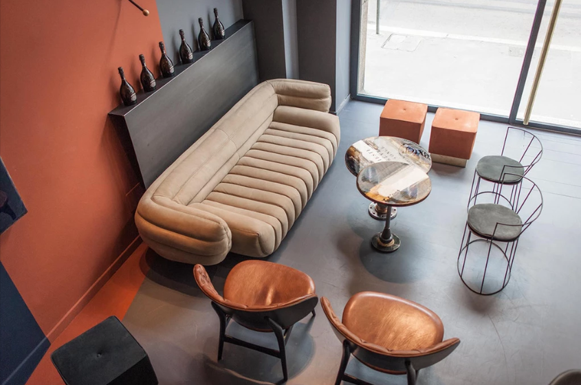 Channelled pale sofa and rounded chairs arranged in a room with rust-coloured walls.