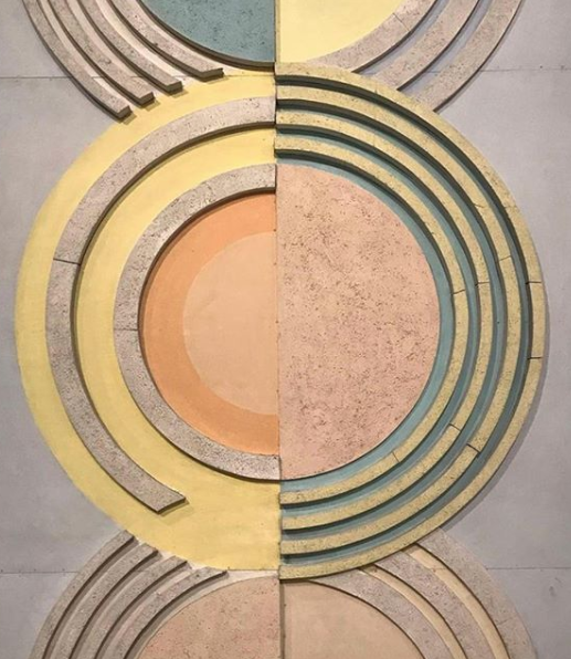 Circular geometric rug pattern in muted gold, pink and green tones.