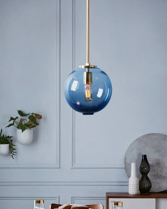 Blue glass globe pendant suspended against pale blue wall panelling.