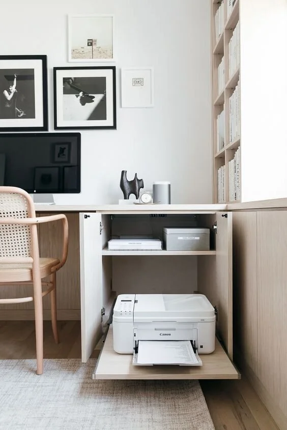 Compact pale desk and timber chair beneath framed monochrome photographs.
