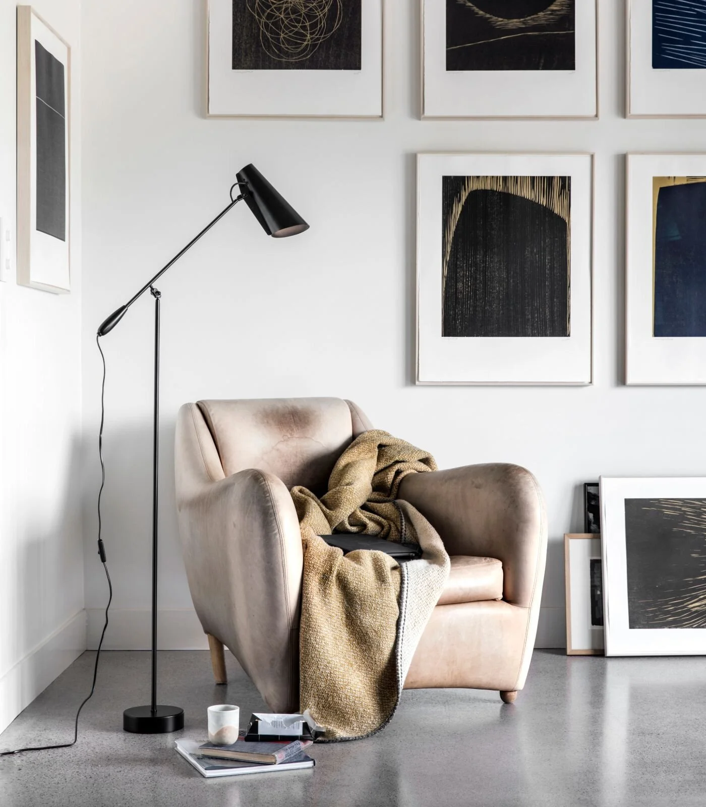 Upholstered reading chair and floor lamp beneath a wall of framed photographs.