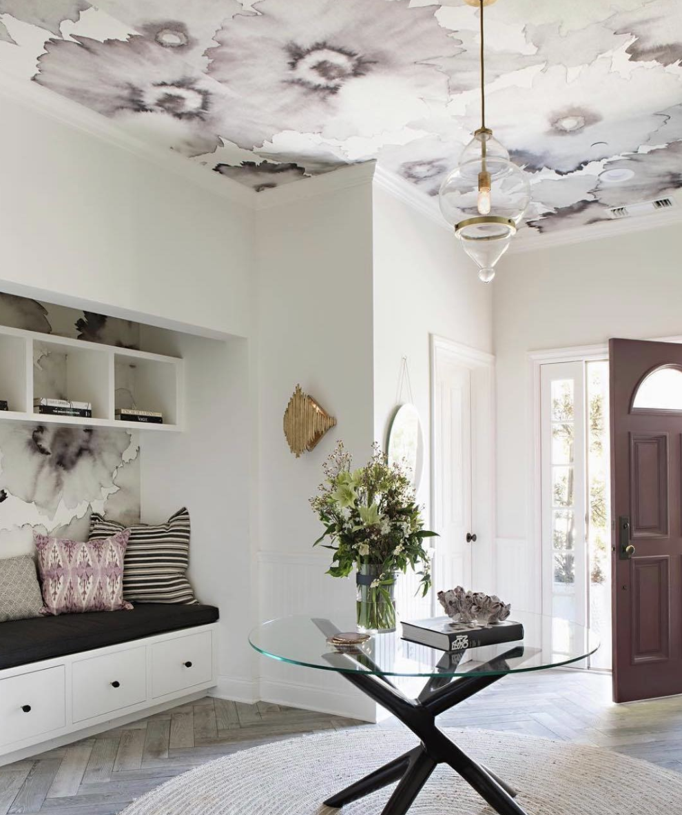 Patterned ceiling above a pale room with a pendant light and glass table.