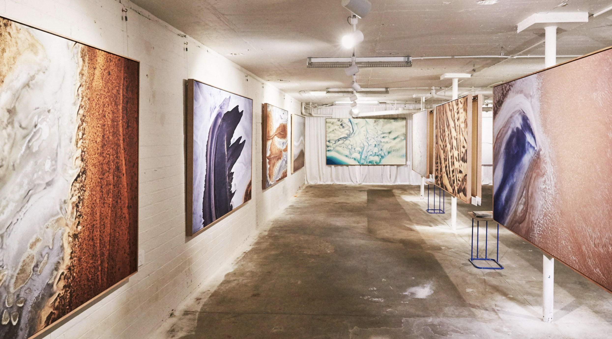 Gallery interior displaying large artworks along pale walls.