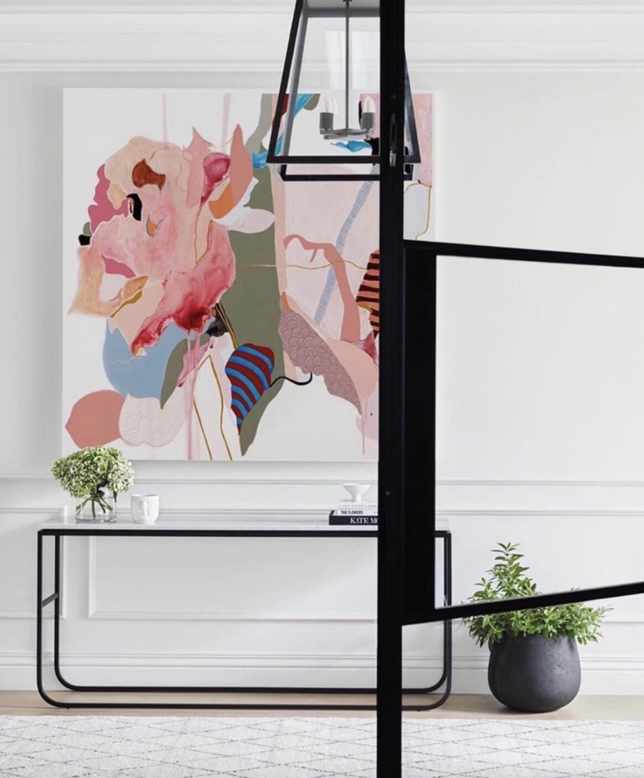 Colourful abstract artwork above a slim console beside black-framed glazing.