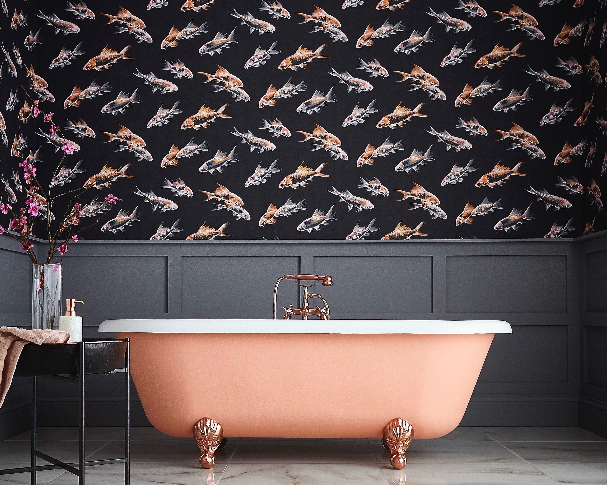 Pink freestanding bath beneath dark patterned wallpaper and wall panelling.