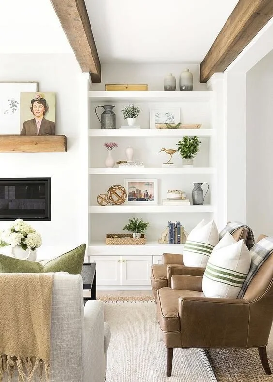 Pale living room with open shelving, timber ceiling beams and upholstered seating.