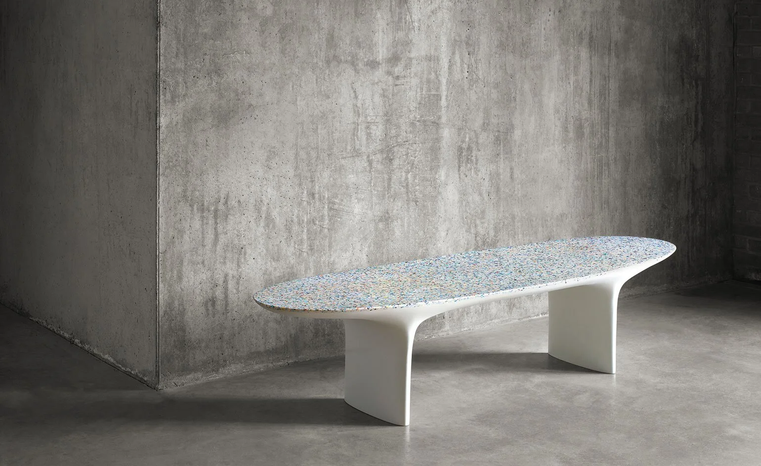Low pale sculptural stone table against a textured grey wall.