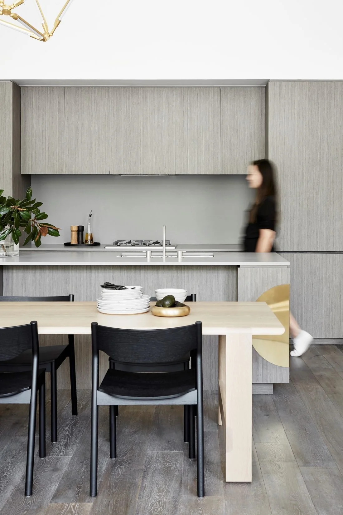 Dining table and black chairs beside a pale contemporary kitchen.