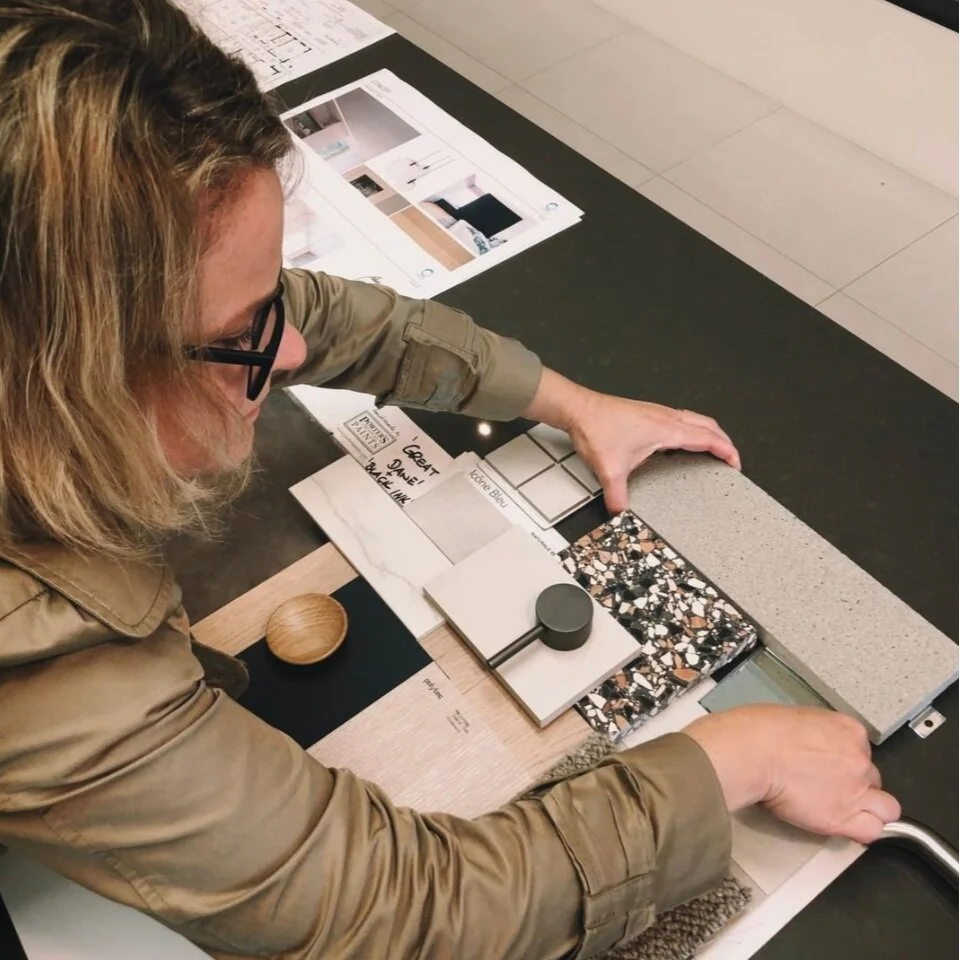 Designer arranging material samples and plans at a worktable.