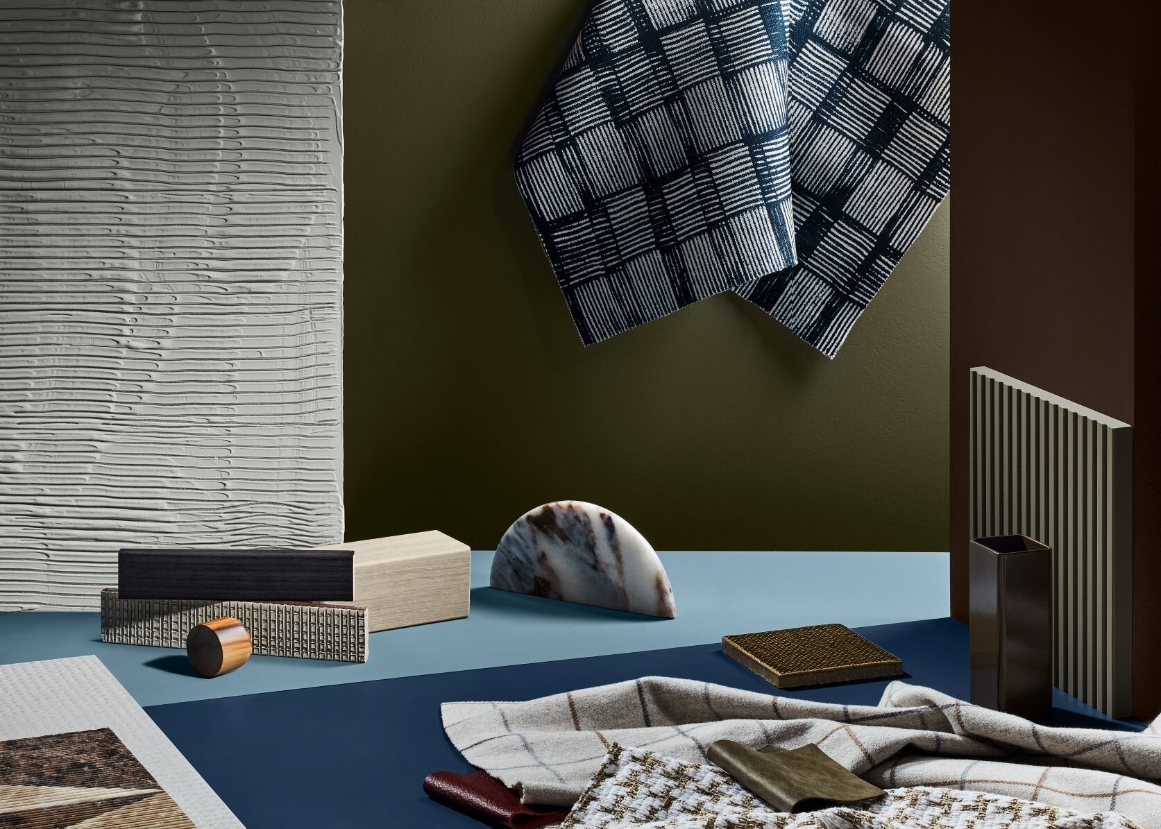 Blue and grey material samples with textured fabrics against a dark green background.