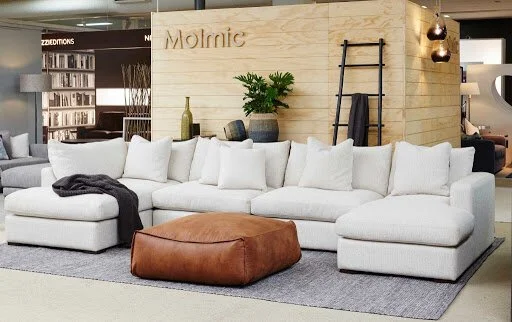 Furniture showroom displaying pale modular sofas and a rust-toned ottoman.