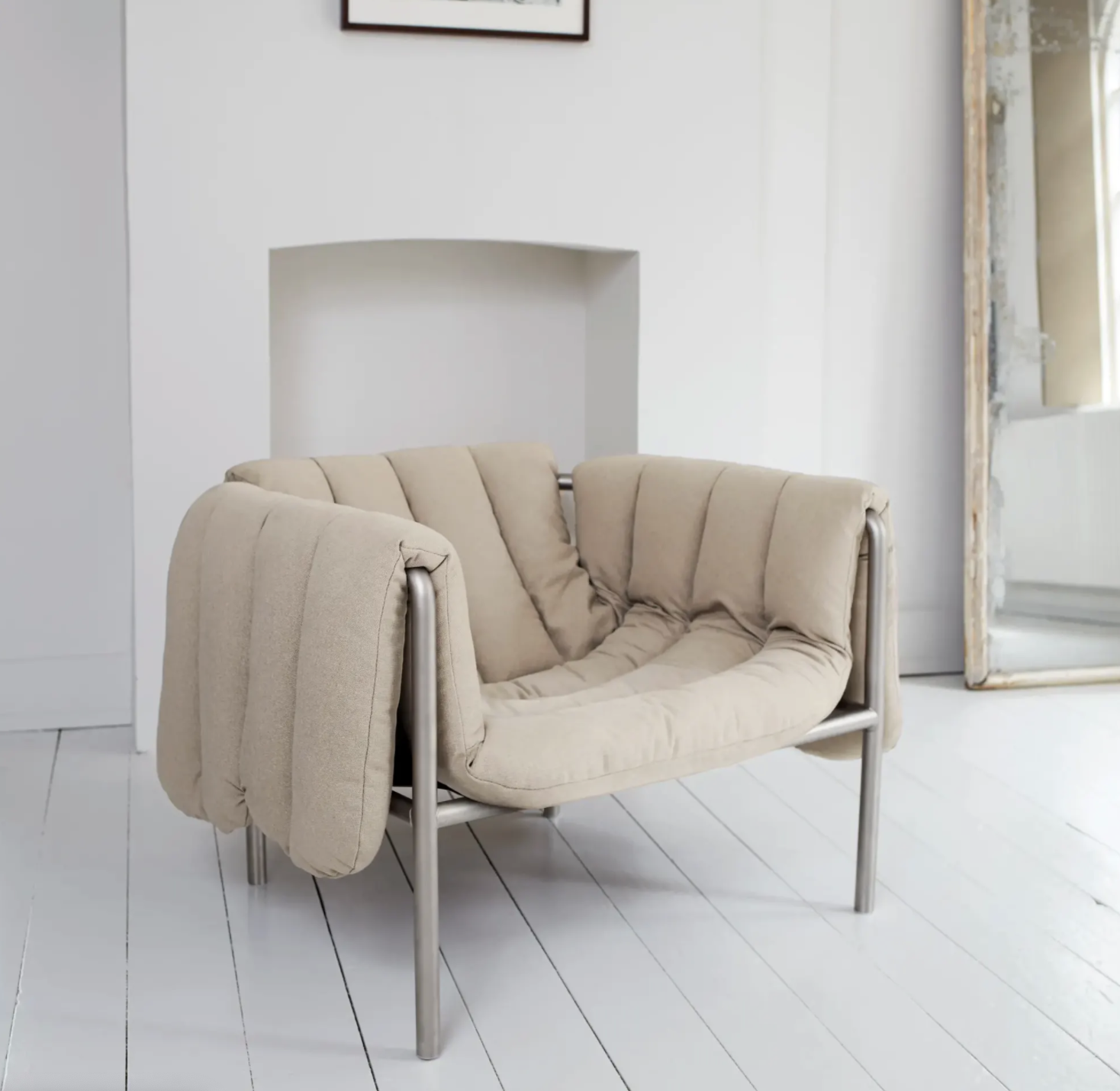 Puffy upholstered lounge chair with an exposed slender metal frame.