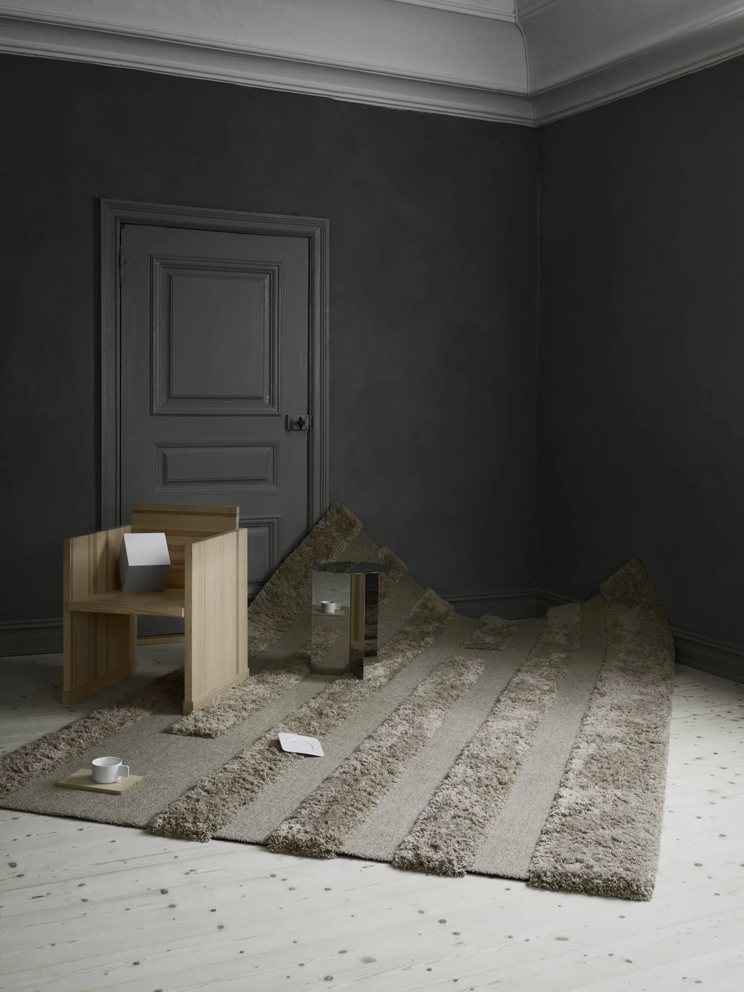 Textured pale rug beneath a timber stool in a dark-painted room.