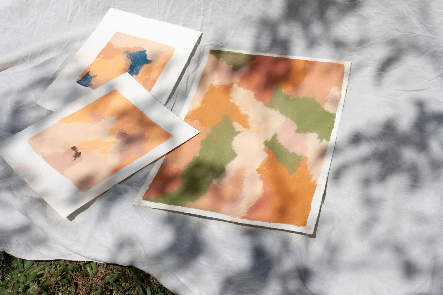 Small pastel artworks with soft orange and green abstract compositions.